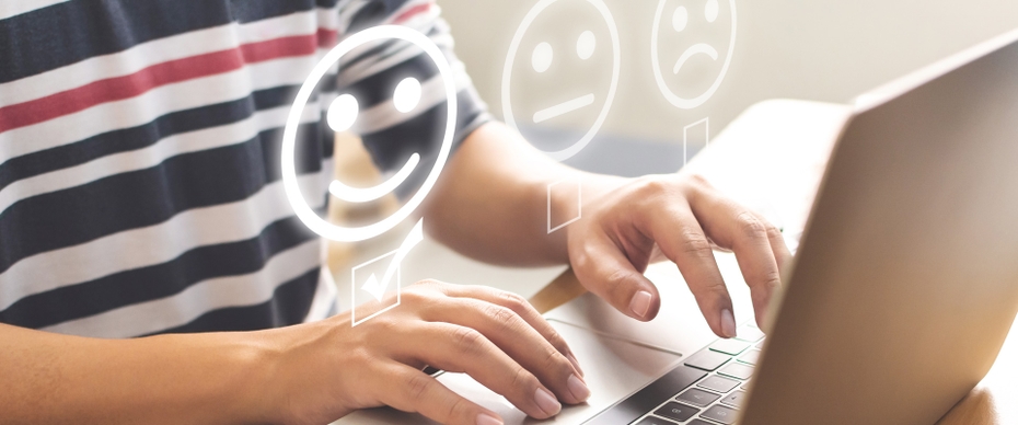 A student sits in front of an open laptop. Above the laptop are illustrated happy, neutral, and sad faces with boxes below indicating the individual is completing a satisfaction survey.