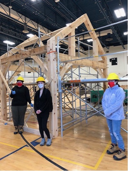 Students stand beside the finished timber frame structure.