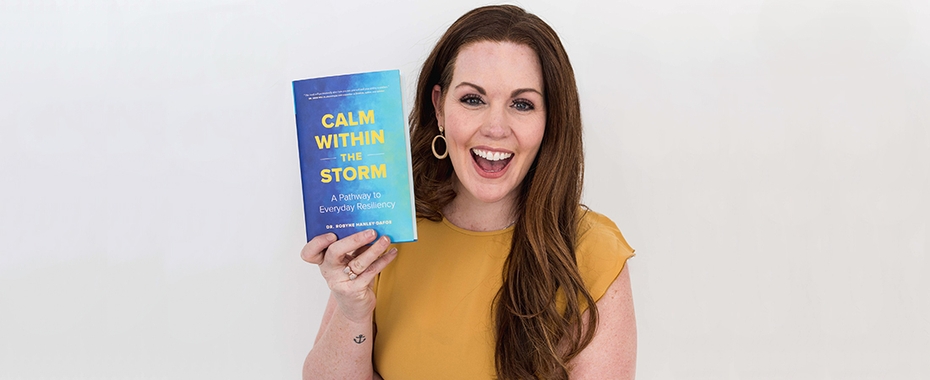 Dr. Robyne Hanley-Dafoe smiles as she holds up her book Calm Within the Storm
